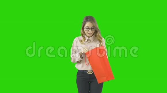 一位身穿节日服装的年轻女子打开礼物为自己的礼物感到高兴在一个孤立的背景下拍摄视频的预览图