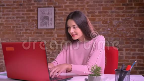 快乐的白种人女商人坐在笔记本电脑前的桌子旁一边高兴地跳舞一边发牢骚视频的预览图