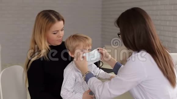 一个戴着医疗面具的小男孩在儿科医生的招待会上的特写视频的预览图