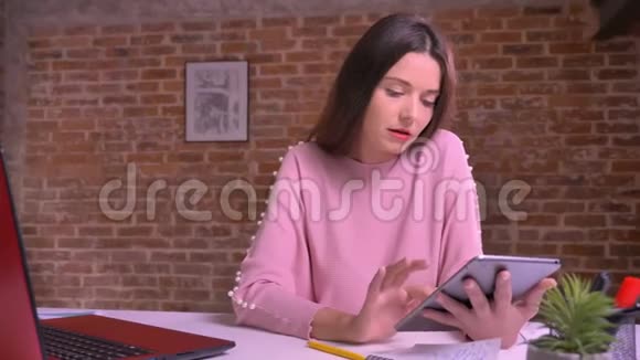 一位漂亮的白人女士在红工作室的办公桌上轻松地打字视频的预览图