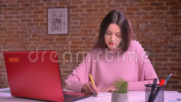 高加索女商人在电脑上工作写笔记看上去很有动力而且在室内很有效率视频的预览图