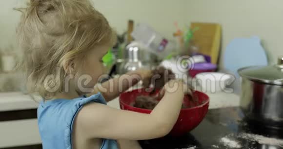 孩子把巧克力面团混合女孩在厨房做蛋糕视频的预览图