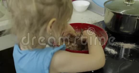 孩子把巧克力面团混合女孩在厨房做蛋糕视频的预览图