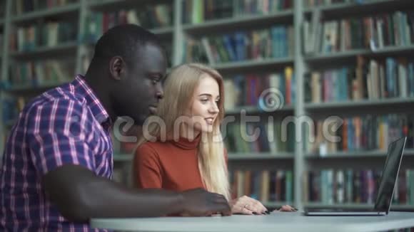 女孩和她的非裔美国朋友正在向笔记本电脑的摄像头挥手告别视频的预览图