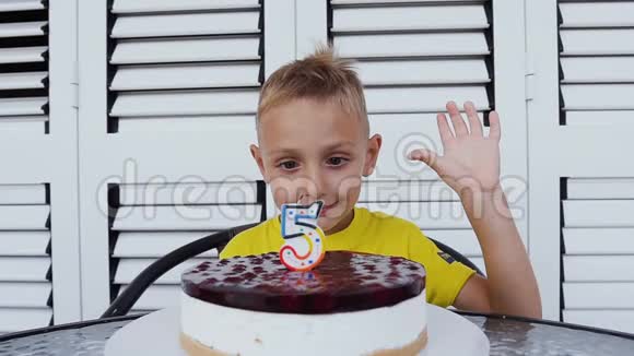 可爱的快乐男孩庆祝它的五岁生日在他面前美味的蛋糕与蜡烛的形式5快乐视频的预览图