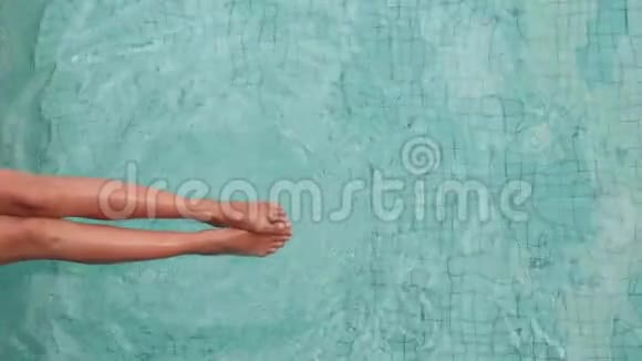 穿着白色泳衣的年轻性感女人坐在泳池边喝着蓝色的水视频的预览图