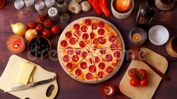 把意大利辣香肠披萨和蔬菜和蜡烛旋转在桌子上视频的预览图