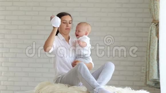 年轻的妈妈在卧室的家里给一个哭泣的小婴儿舒缓特写镜头视频的预览图