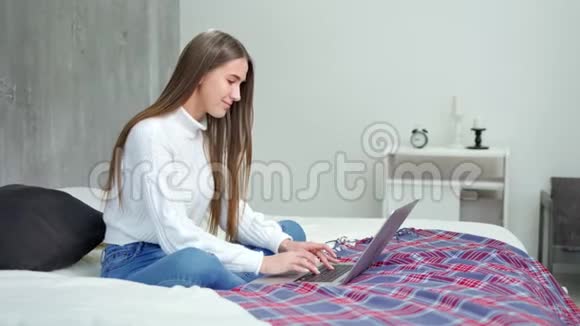 微笑年轻的自由职业者女士用笔记本电脑全镜头键盘输入文字视频的预览图