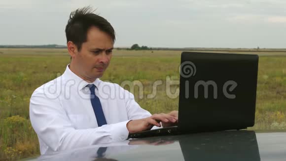 穿白衬衫和领带的商人在车顶的笔记本电脑键盘上写文字视频的预览图