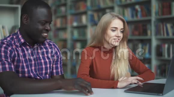 非裔美国人和欧洲人金发碧眼一边聊天一边看着笔记本电脑视频的预览图
