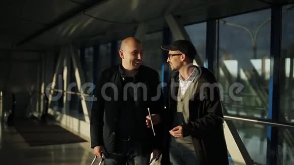 机场的两名男子沿着走廊寻找航班上的接待处视频的预览图