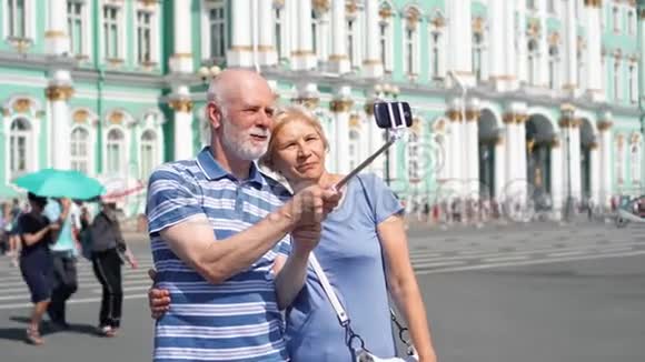 在俄罗斯圣彼得堡皇宫广场上的老夫妻在度假时用手机自拍视频的预览图