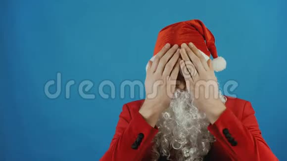 圣诞节像圣诞老人一样的人用手掌遮住眼睛2019年新年蓝色背景视频的预览图
