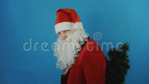 2019年新年像圣诞老人一样的人背着一棵圣诞树伸出大拇指像蓝色的背景视频的预览图