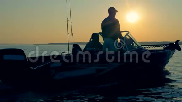 快艇漂浮在湖面上船上有两个钓鱼者和捕鱼设备视频的预览图