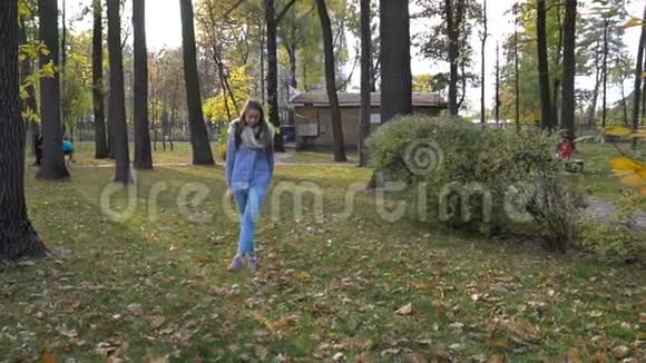 美丽的年轻女子戴着针织围巾在秋天的公园散步视频运动视频的预览图