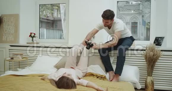 一对情侣在卧室里拍了几张照片年轻人在舒适的床上为女友拍照留念视频的预览图