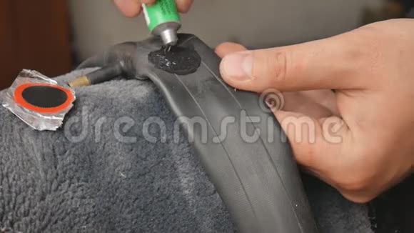 自行车或机械师正在在穿孔的内管上涂上胶水双手合拢自行车轮胎爆胎一个男人视频的预览图