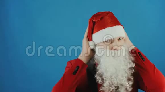 圣诞节像圣诞老人一样的人用手掌捂住耳朵2019年新年蓝色背景视频的预览图