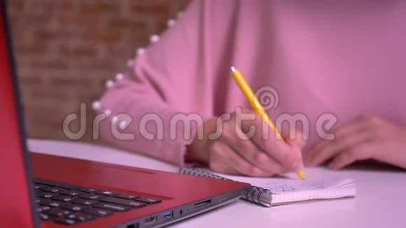 成年白种人女性满怀信心地写下笔记本电脑上的笔记并在桌旁轻松自如视频的预览图