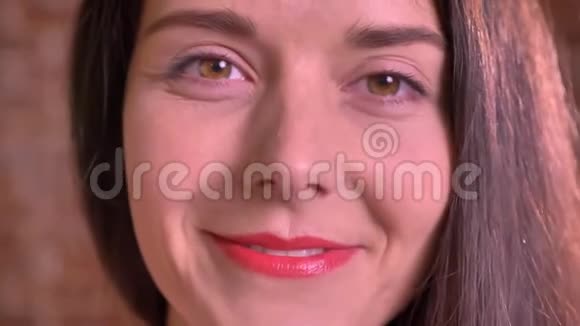 一张可爱的白种人女人的特写脸直看着镜头露出灿烂的微笑和棕色的眼睛视频的预览图