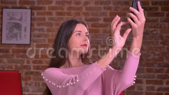 白白种人的商界女性在工作室里轻松地在砖墙前自拍和寒蝉视频的预览图