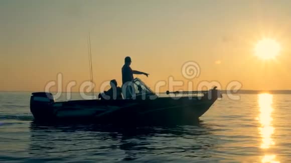 日出景观两个人装备钓鱼航行在开阔水域视频的预览图