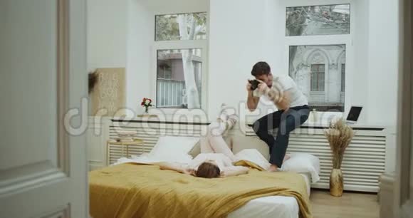 照片时间在卧室里年轻夫妇在床上为回忆拍照美丽的时刻在一起视频的预览图