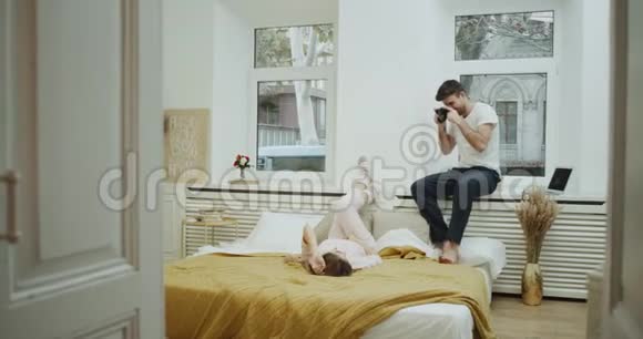 在卧室里设计的令人惊叹的舒适设计一对夫妇在一起度过浪漫的时光男人为这位女士拍了一些照片视频的预览图