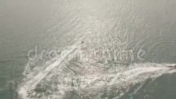 人们乘坐水上喷气式滑雪板在蓝色的海洋在日落鸟瞰Drun看到人们在露天水中驾驶喷气式滑雪板视频的预览图