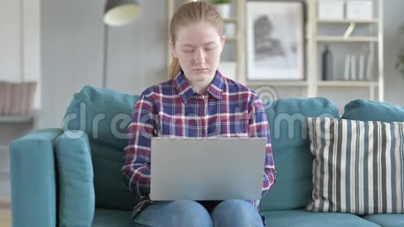 坐在沙发上用笔记本电脑的年轻女人视频的预览图