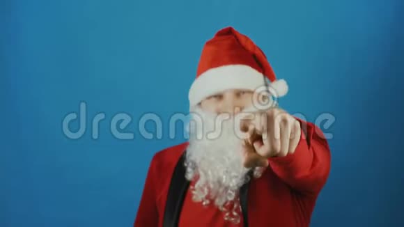 圣诞节像圣诞老人一样的人在镜头里伸出食指新年在蓝色的背景上视频的预览图
