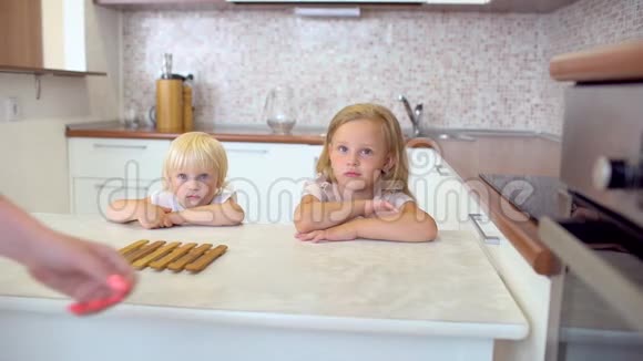 在背景上小女孩微笑着从烤箱里拿出热饼干在家厨房里很开心视频的预览图