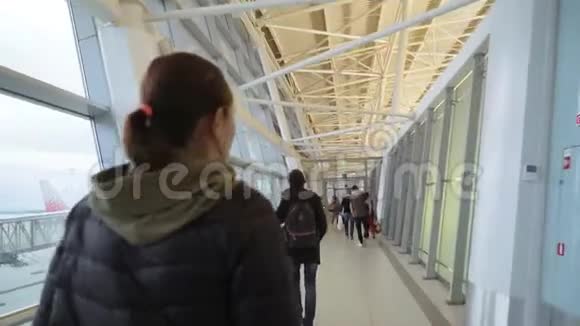 一个穿黑色夹克的女人和她的女儿正沿着机场大楼的走廊走一起射击视频的预览图