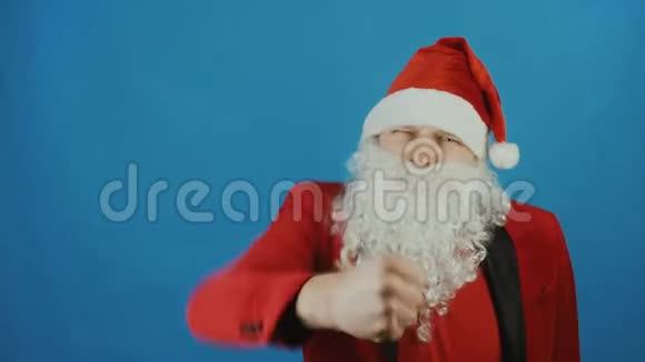 圣诞节和2019年新年像圣诞老人一样的人在镜头前在蓝色背景上展示拳头视频的预览图