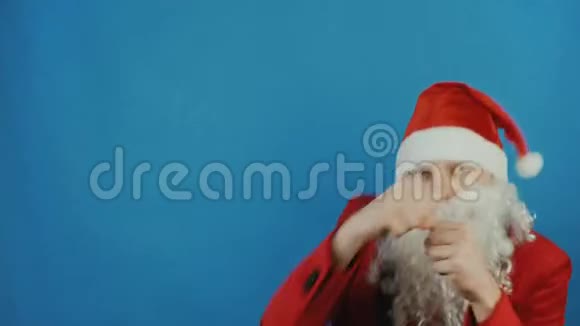 圣诞节和新年像圣诞老人一样的人正在拳击在蓝色背景下用拳头向镜头挥拳视频的预览图