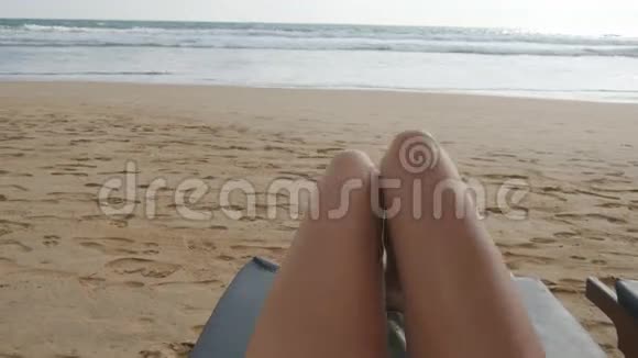 年轻女子躺在海边晒日光浴的角度女性双腿在躺椅上放松和享受视频的预览图