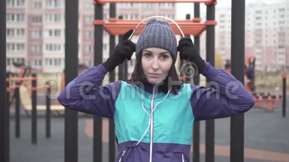 街头操场上戴着耳机的女运动员肖像慢莫视频的预览图