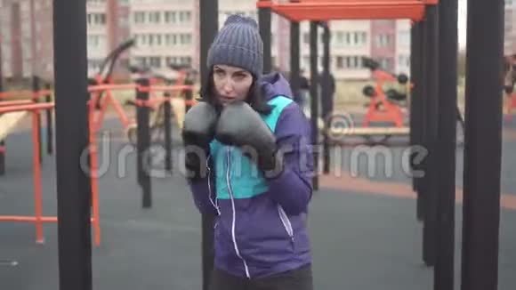 女子拳击手套拳击在街头训练场与影子搏斗视频的预览图