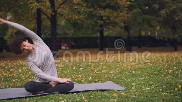 苗条的女孩正在做瑜伽运动以健康的脊柱伸展身体和手臂然后放松在莲花的位置与视频的预览图