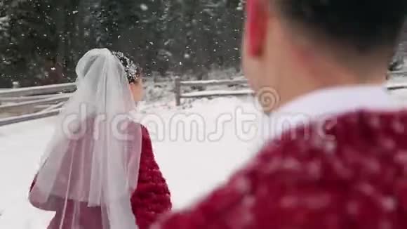 年轻的新娘跑到森林要求新郎跟随她在大雪下在兰乔玩得开心冬季婚礼视频的预览图