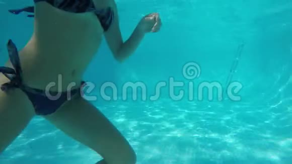 穿着蓝色泳衣的白种人女孩从池水下经过镜头前视频的预览图