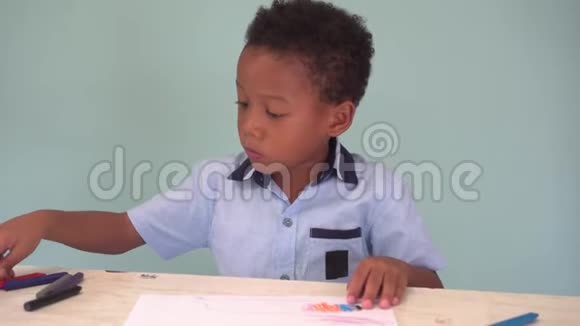 非裔美国男孩学习用蜡笔在桌子上画画视频的预览图