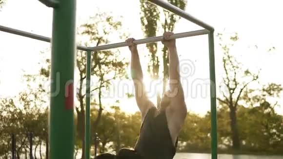 在户外的水平杆上训练健美男子公园里的横梁上有体操特技吗视频的预览图