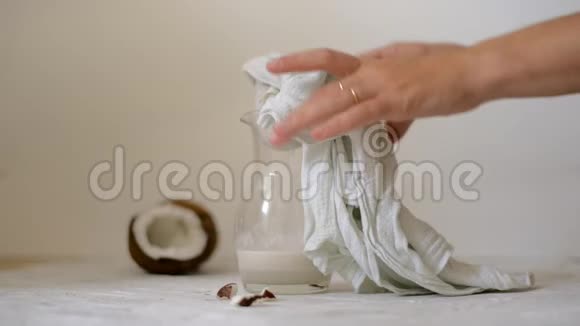 在家准备纯素椰奶的女人把牛奶倒入奶酪布中过滤替代牛奶视频的预览图