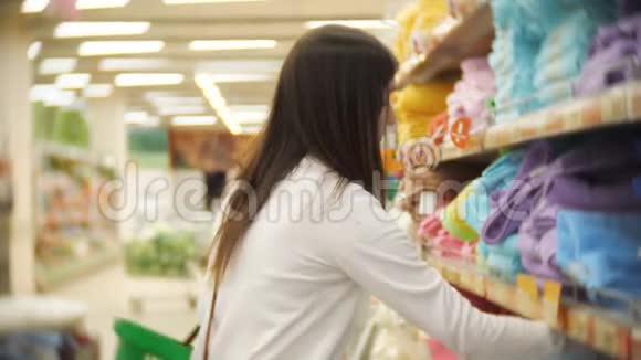 家用纺织品年轻的黑发女人在商店里选择一条毛巾视频的预览图