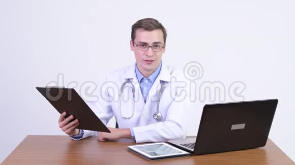 年轻快乐的帅哥医生在木桌上解释什么视频的预览图