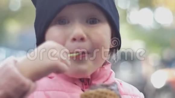 喜气洋洋的女孩戴着帽子在街上吃冰淇淋脸贴得很近视频的预览图