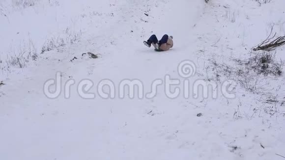 孩子们在冬天的公园里滑过雪橇笑了起来慢动作快乐的女孩从山上滑下雪视频的预览图